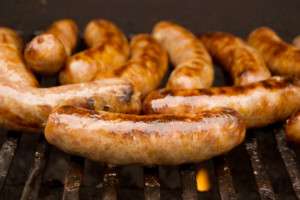 Bratwurst sausages grilling on a barbeque.